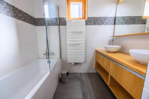 ein Badezimmer mit zwei Waschbecken, einer Badewanne und einer Dusche in der Unterkunft Résidence L'ecrin - ECRIN A22 MAE-0131 in Arc 1800