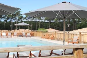 a pool with tables and chairs and an umbrella at Domaine du Ferret Restaurant & Spa in Cap-Ferret