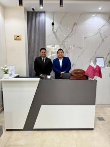 two men are standing at a reception desk at Rawda Hotel in Doha