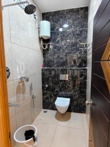 a bathroom with a toilet and a black wall at VISAI Retreat in Tiruvannāmalai