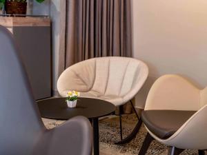 a room with a white chair and a table and chairs at B&B HOTEL Dresden City-Süd in Dresden