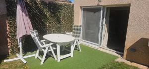 een tafel en twee stoelen en een parasol op een patio bij Studio Tranquillo avec piscine et salle de sport in Istres