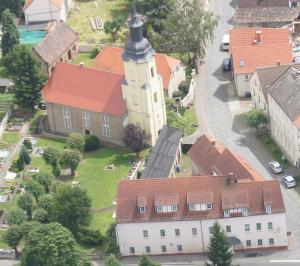 einen Luftblick auf ein kleines Dorf mit einer Kirche in der Unterkunft Hotel Draschwitz in Draschwitz