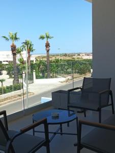 a room with chairs and a table and palm trees at Dara Holiday Apartments in Marsala