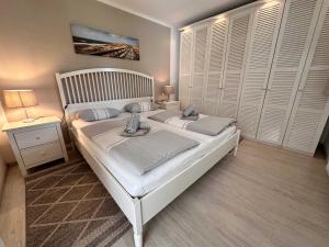 a bedroom with a large white bed and a night stand at Cozy Wohnung fuer 4 Gaeste mit Terrasse unter Reet in Sankt Peter-Ording