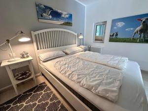 a bedroom with a large white bed and a table at Cozy Wohnung fuer 4 Gaeste mit Terrasse unter Reet in Sankt Peter-Ording