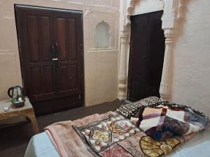 a bedroom with a bed with a wooden door at Kila Todarmal Heritage Stays in Dārāganj