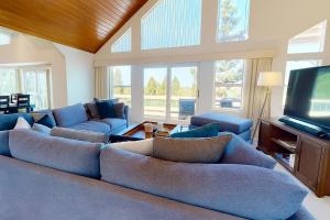 a living room with blue couches and a flat screen tv at Sleek Hill Haven with Martis Valley Views in Polaris