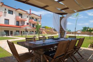 een terras met een tafel en stoelen en een gebouw bij Anthemida Rooms in Sikia