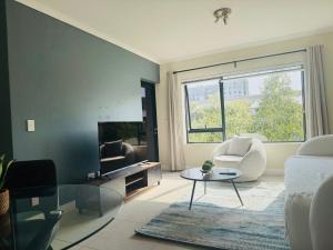 a living room with a couch and a table and a tv at Manhattan Corner in Cape Town +3 photos