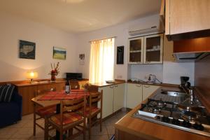 a kitchen with a table and a small table and a kitchen with a stove at Apartment Josip in Risika