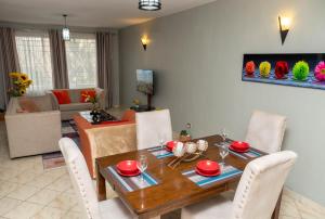 Una sala de estar con una mesa y sillas de madera. en Perfect Palm Condos-F16, en Nakuru