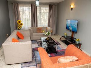 sala de estar con muebles de color naranja y TV en Perfect Palm Condos-F16, en Nakuru