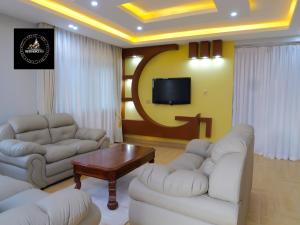 a living room with white couches and a tv at Residence Six Sigma in Entebbe