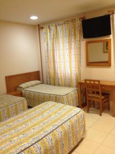 ein Hotelzimmer mit 2 Betten und einem TV in der Unterkunft Hostal Aeropuerto in Madrid