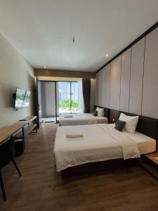 a hotel room with two beds and a desk at M-LIVIN Hotel in Pangkalpinang +71 photos