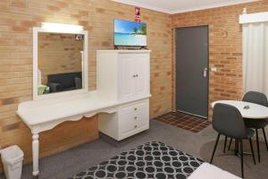 a room with a white desk and a mirror at Cousins Motor Inn in Inverell