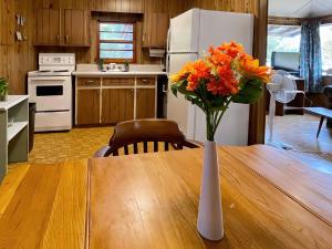 un jarrón de flores naranjas sentado en una mesa en una cocina en Balsam Lake - 2-Bedroom Cottage #2, en Kawartha Lakes