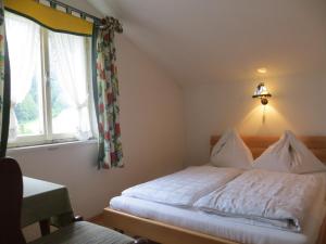 Schlafzimmer mit einem weißen Bett und einem Fenster in der Unterkunft Garni Haus Jagerwirt in Fuschl am See