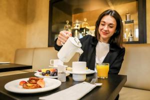 a woman sitting at a table with a plate of food at Theresian Hotel in Olomouc +56 photos