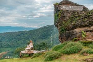 una donna seduta su un tavolo davanti a una cascata di Phupetra ภูเปตรา a Ban Thung Phan Ha Altre 60 foto