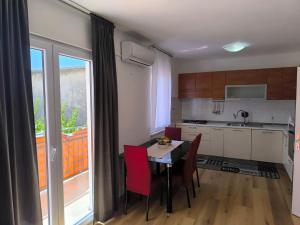 a kitchen with a table with red chairs and a window at Apartment IMB in Primošten +7 photos