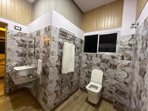 a stone bathroom with a toilet and a sink at Aam Bagan in Chunchura +37 photos