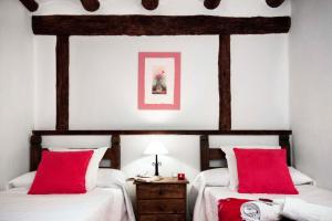 a bedroom with two beds with red pillows and a table at Casa La Sabina Rural in Calomarde