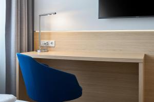 a desk with a blue chair in a room at Four Points Flex by Sheraton Göttingen in Göttingen