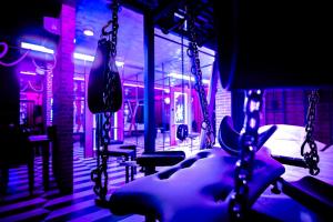 une salle de sport avec des balançoires dans une pièce avec des lumières violettes dans l'établissement Nikisz Red BDSM, à Katowice