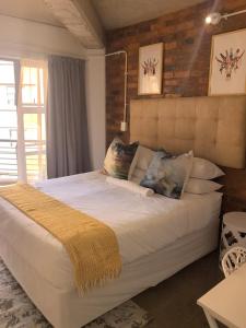 a bedroom with a large bed with white sheets and pillows at Stylish Modern Apartment in the heart of Maboneng, Free Wifi and Netflix in Johannesburg