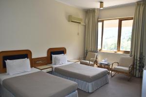 テノムにあるHotel Perkasa Tenomのベッドが2つと窓があるホテルの部屋