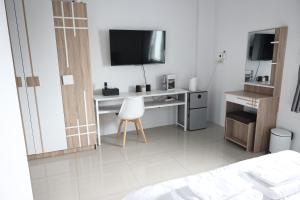 a bedroom with a desk with a television and a chair at Papaya Stay in Sathani Khlong Rian
