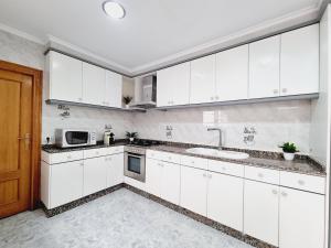 Una cocina blanca con fregadero y microondas. en La Maison du Port, en Puerto Sagunto