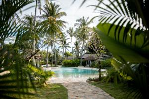 a resort swimming pool with palm trees in the background at Kuara Lombok in Bumbang +81 photos