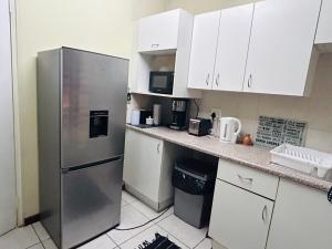 a kitchen with a stainless steel refrigerator and white cabinets at Cozy appartement in Roodepoort