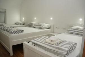 two beds in a white room with towels on them at Sobe Ritz in Požega