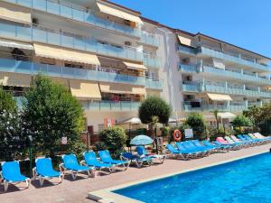 a hotel with chairs and a swimming pool and a building at Alegre apto con piscina, a 300m de la playa. in Blanes
