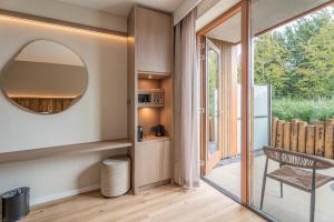 een kamer met een spiegel, een stoel en een balkon bij Strandhotel Duinoord in Vrouwenpolder