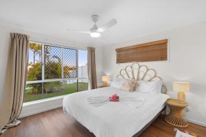 een slaapkamer met een wit bed en een groot raam bij Waterfront holiday home in Banksia Beach +32 foto's