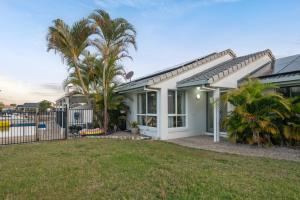 een huis met een palmboom in de tuin bij Waterfront holiday home in Banksia Beach