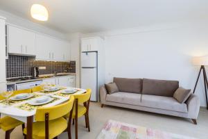 a kitchen and living room with a table and yellow chairs at Yenier Apart Kas in Kaş