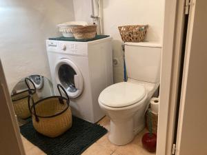 a bathroom with a toilet and a washing machine at Studio with large private courtyard in Boucau