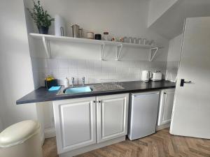 a white kitchen with a sink and a white refrigerator at Riviera Loft Penzance in Penzance