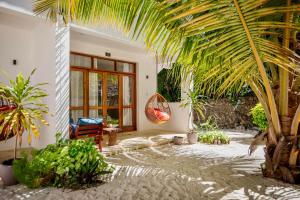a patio with a chair and a palm tree at Mnana Beach Bungalows in Michamvi