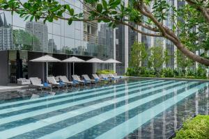 a swimming pool with chairs and umbrellas at La Clef Bangkok by The Crest Collection in Bangkok