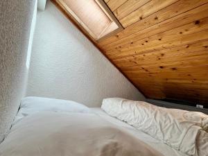 un lit dans une chambre avec un plafond en bois dans l'établissement Studio cosy au centre de Samoëns avec balcon - FR-1-624-183, à Samoëns