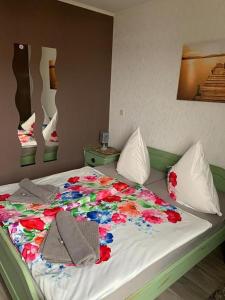 a bed with a flower blanket on it at Hotel Auberge Restaurant in Schorfheide