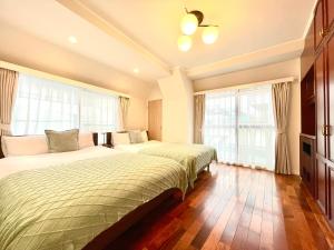 twee bedden in een slaapkamer met ramen en houten vloeren bij Modern Tokyo Suites in Tokyo
