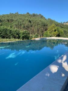 a pool of blue water with a mountain in the background at Casa de Rompecias in Vizela